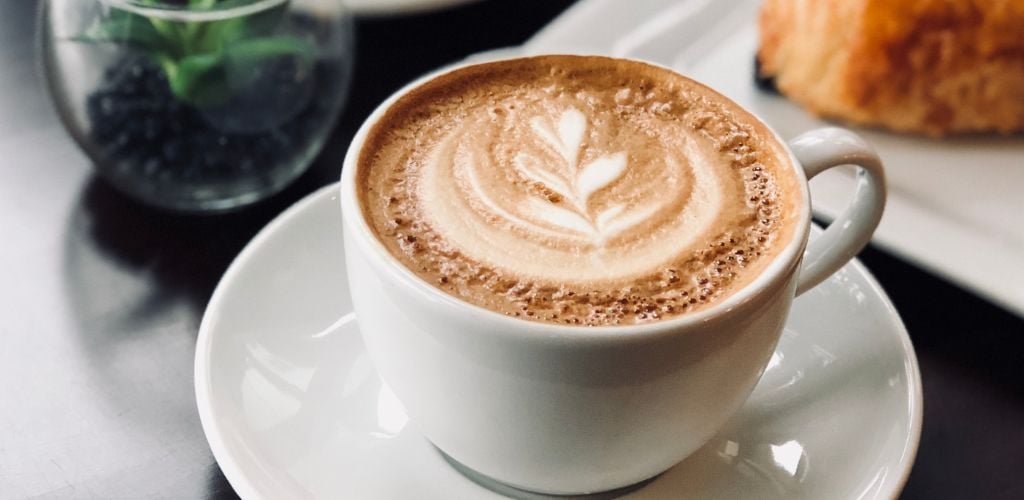 Cup of delicious coffee with froth on breakfast in cafeteria