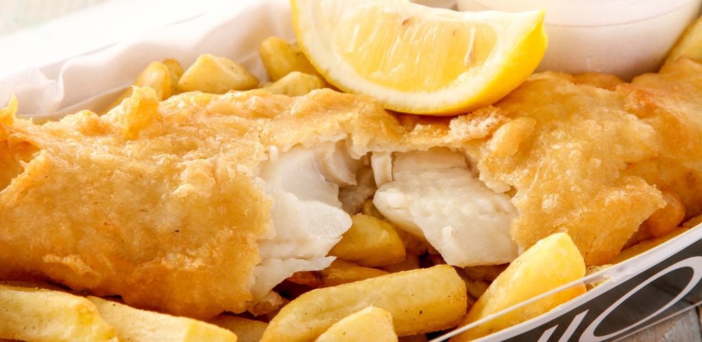 Traditional British battered fish and chips with lemon on the top. 