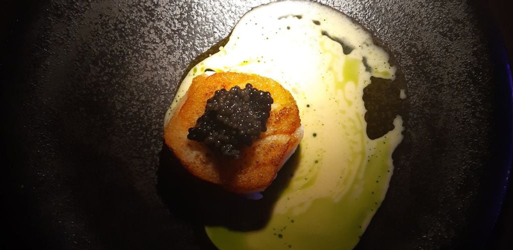 A little dish with caviar on top and a white sauce 
