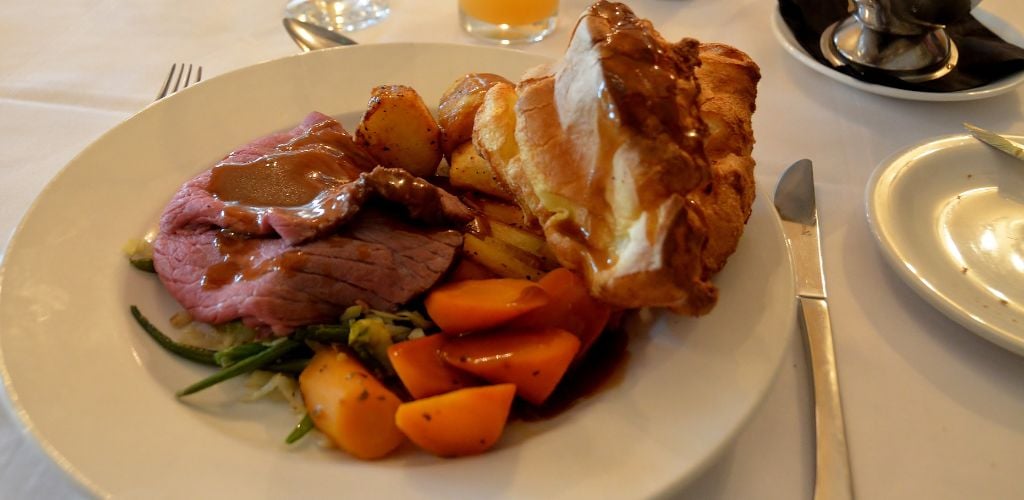 Roast beef with green veggies, marble potatoes, and carrots on the side. 