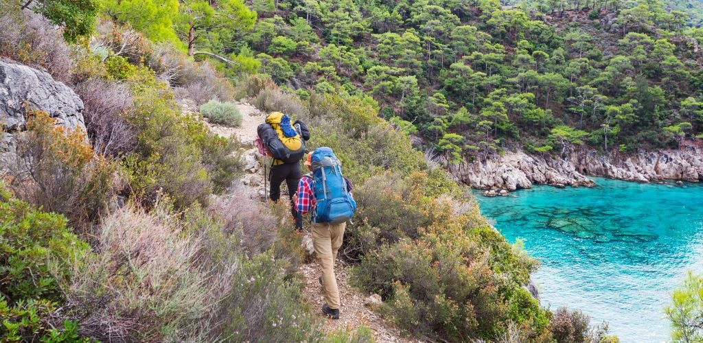 Two hikers hiking in a beautiful natural landscape in Turkey mountains and clear water on the side. The Lycian way is famous among hikers. 