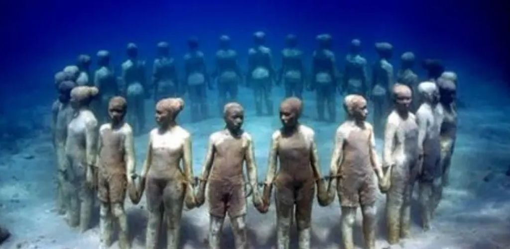 Is a statue of females holding hands in a circular formation. beneath the sea. 