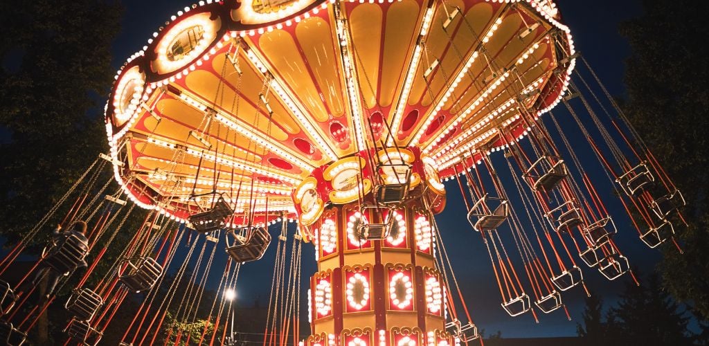 Illuminated swing chain carousel in amusement park at night. 