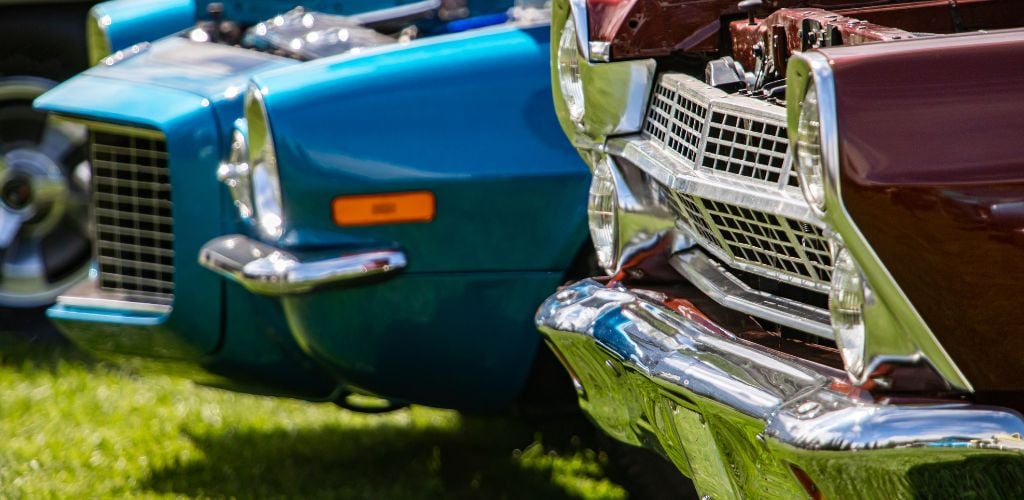 A bumper of maroon and blue vintage car parked. 