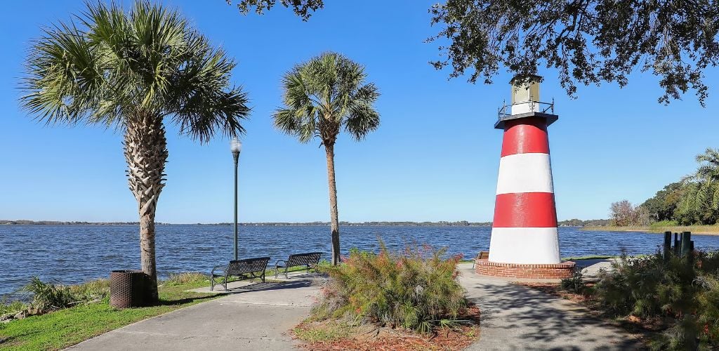The lighthouse at Mount Dora a trees and two benches facing the sea.