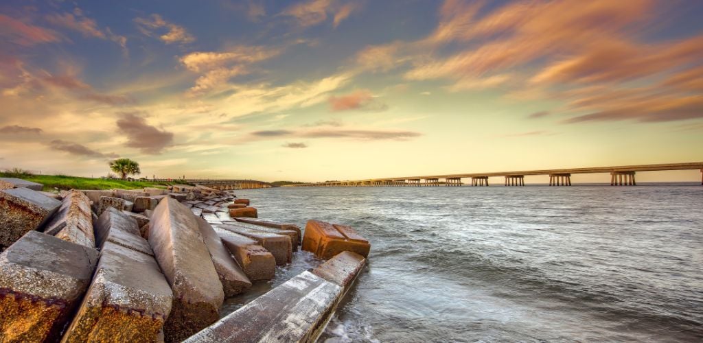 A large stone on the side sea and an extensive bridge in the middle of the water. at sunset 