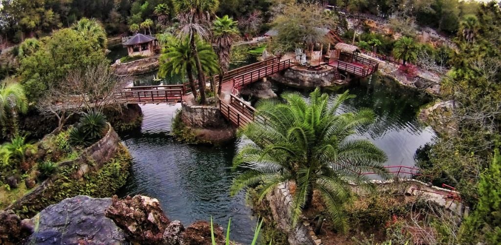 A connecting bridge flanked by a garden and a lake. 