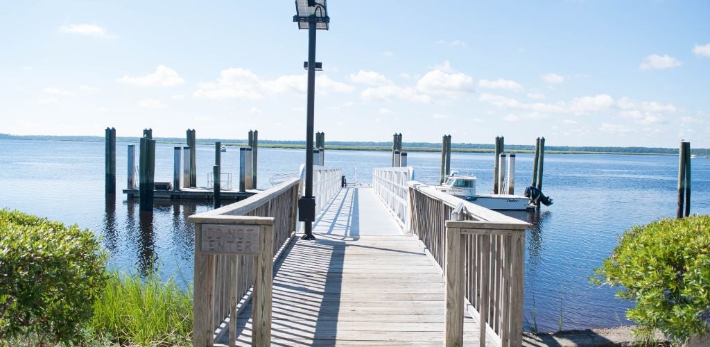 A small pier with a parked small boat, a solar light, and a beach view. 