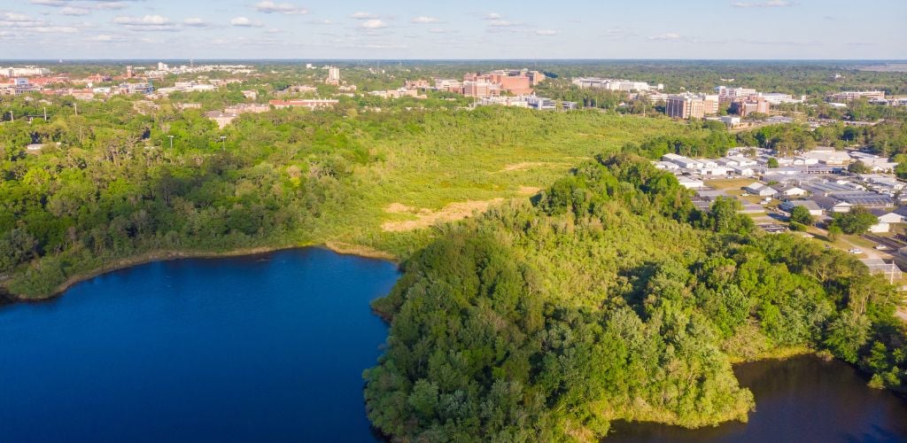 An Aerial view of green mountains, lakes, and building structures. 