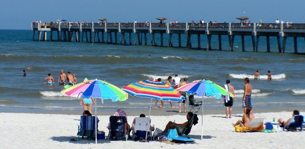 People enjoy the afternoon on Jacksonville Beach and the pier in the background. 