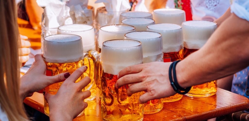 A woman and a man grab a glass of beer on a table at a beer festival. 