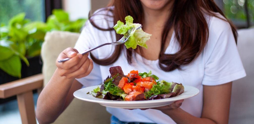 A young woman eating a salad. 