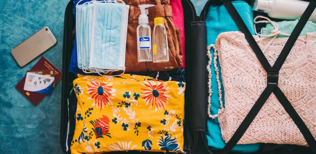Suitcase for vacation trips, including face masks and travel-sized antibacterial hand gels.