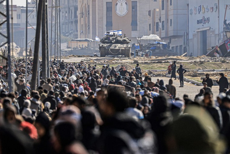 An Israeli tank and other military vehicles guard a position as Palestinians flee Khan Younis in the southern Gaza Strip on January 26, 2024.