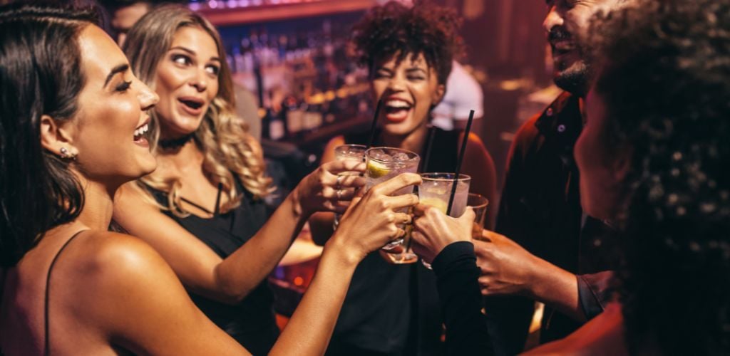 Group of friends partying in a nightclub and toasting drinks. 