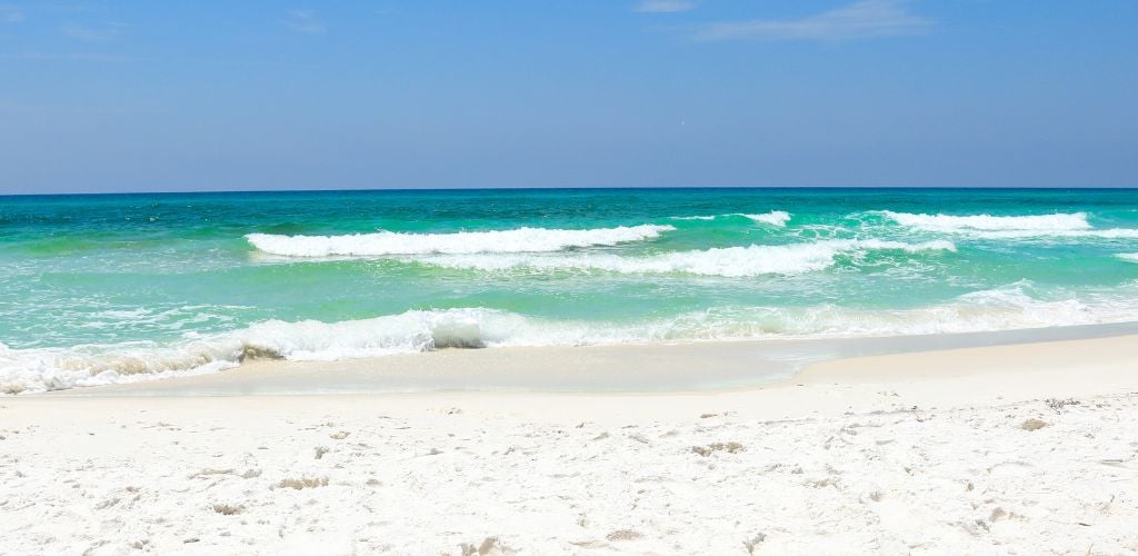 Waves hitting the sugar white beach on a windy day. Vivid sky colors.