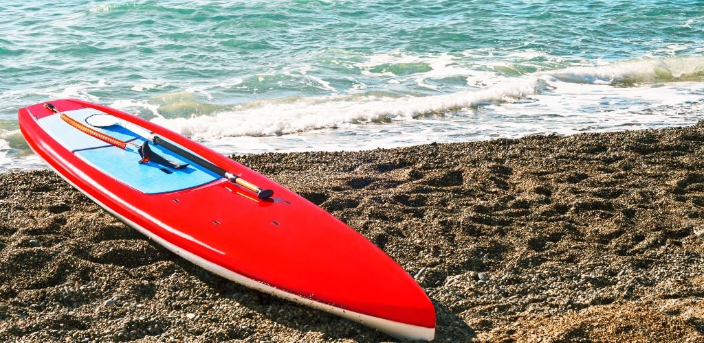 Red board for stand-up paddle surfing on the sea beach. 