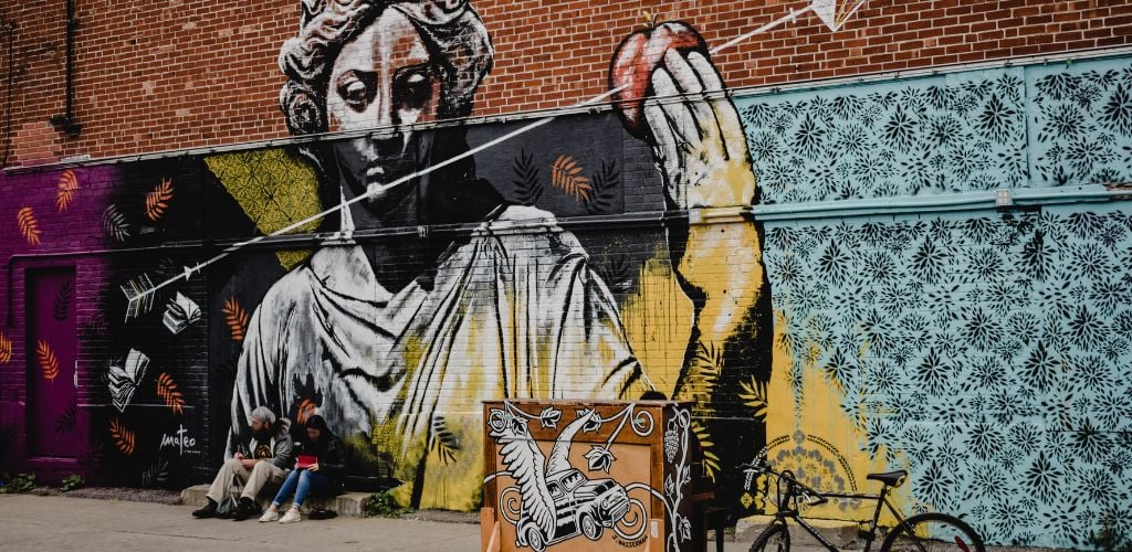 Street Art on Brick Wall. A man and a woman sitting on the side street. 