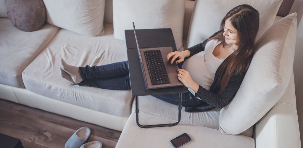 A woman sitting on the couch and using a laptop. 