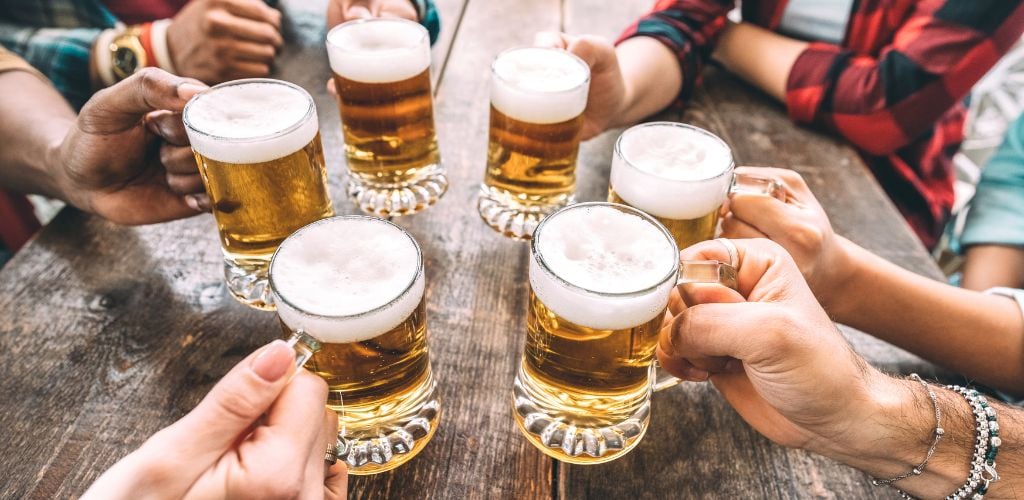 Friends Hands Toasting Beer Pints at Brewery Pub Restaurant.