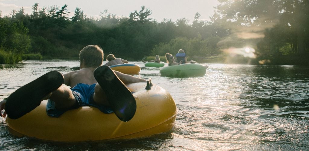 Young people floating down the river in inner tubes. 