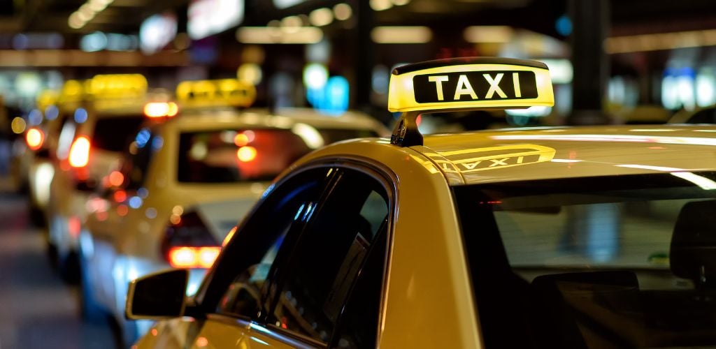 A yellow taxi waiting on the side street. 