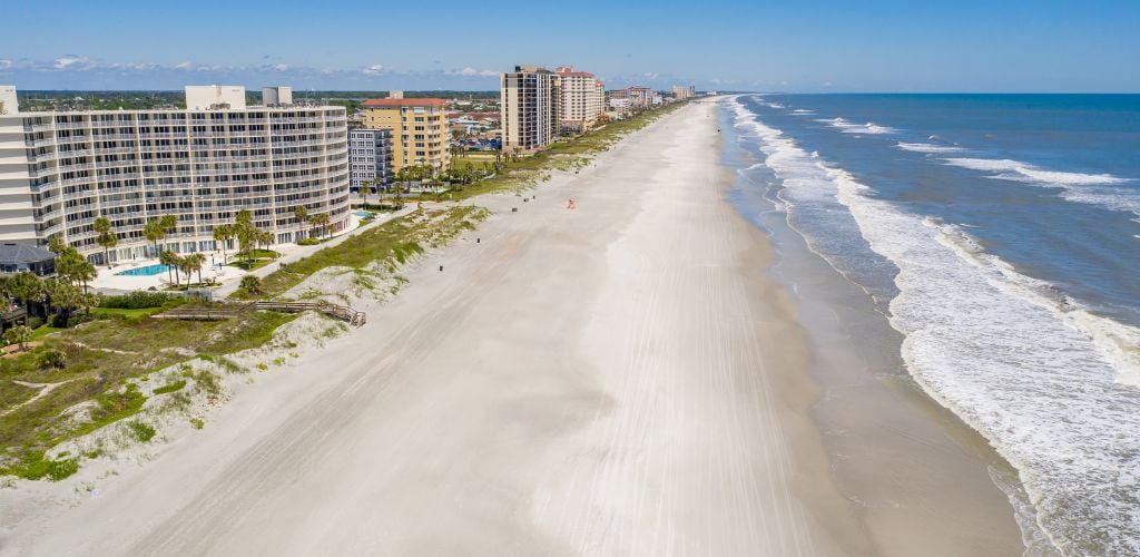 A nice beach with a hotel on the side and clean sea water. 