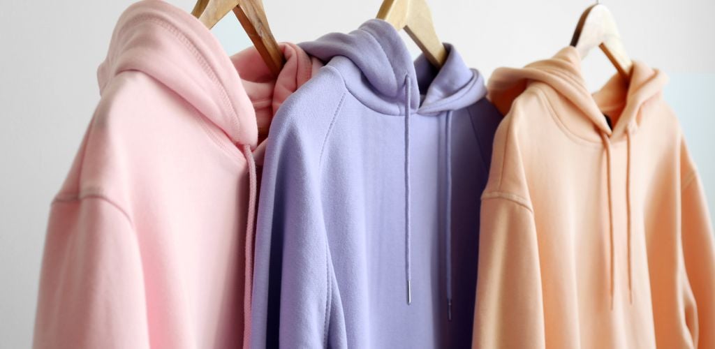 A pink, purple and orange modern Hoodies Hanging on Light Wall