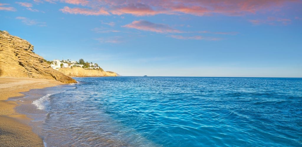 A beautiful beach and a rock-side hill under the sunset. 