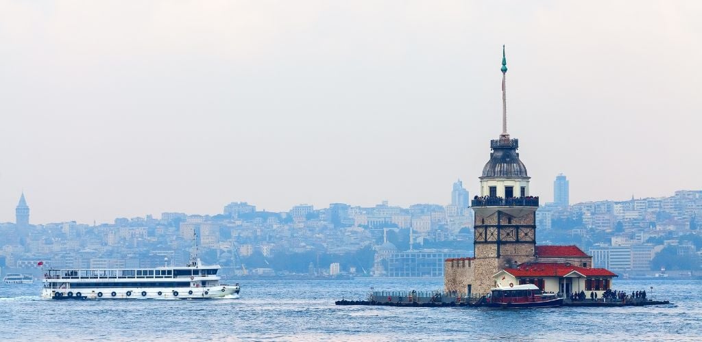 A ferry port, a ferry heading into the dock, and a magnificent background of Istanbul city. 