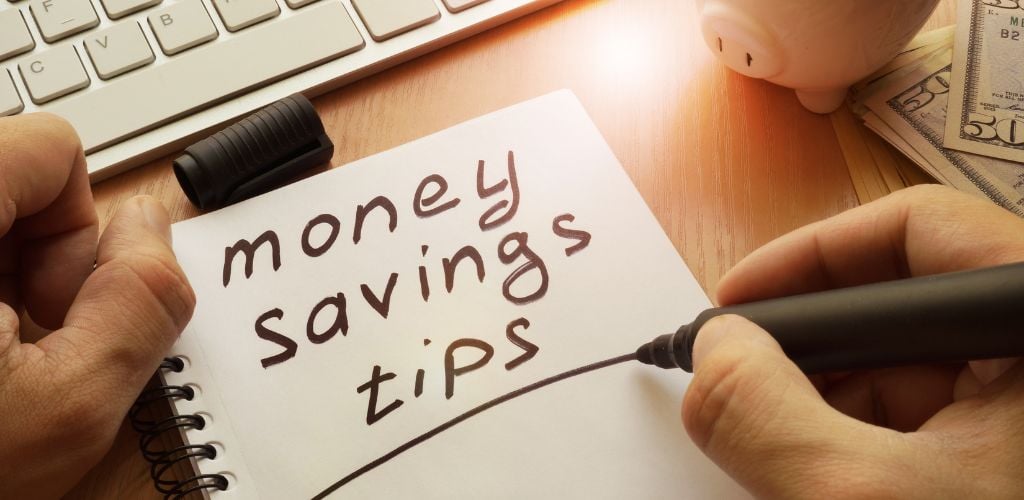 Savings advice is written in a note. On the side are some cash, a pig toy, and a keyboard. 