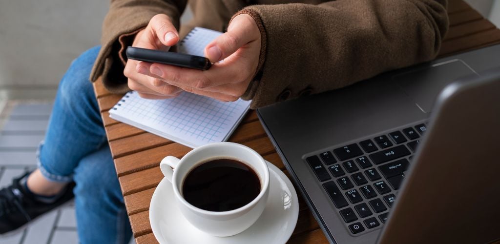 Woman Working in Street Cafe with Laptop using Mobile Phone