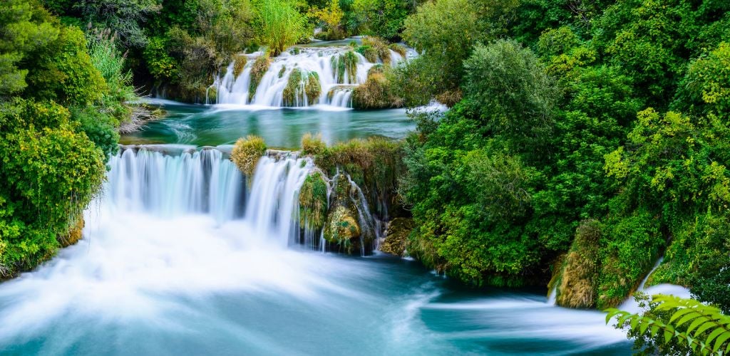 Layers of clear waterfall and surrounded by green trees 