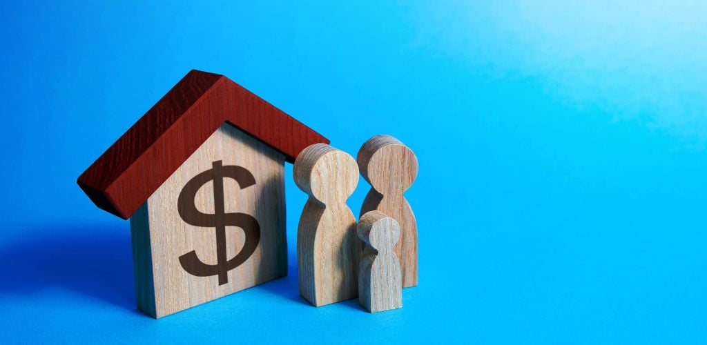 A house with a dollar sign and a family shaped model made of wood