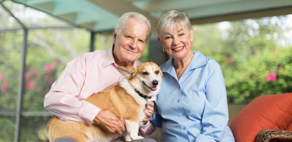 Senior couple posing with a wales corgi dog at terrace.