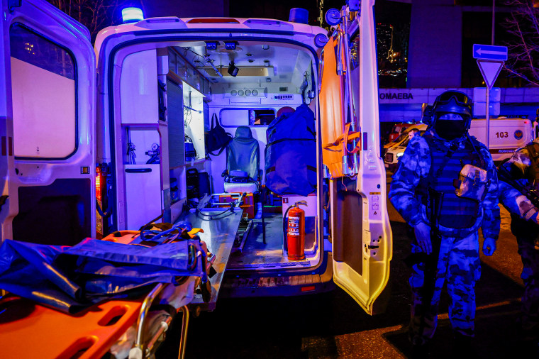 Russian law enforcement officers stand guard near the burning Crocus City Hall