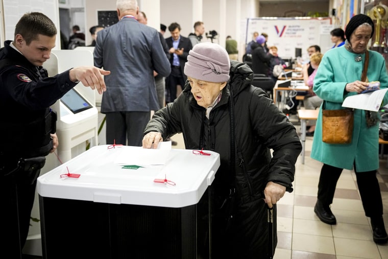 Police officer explains a woman how to cast a ballot during a presidential election.