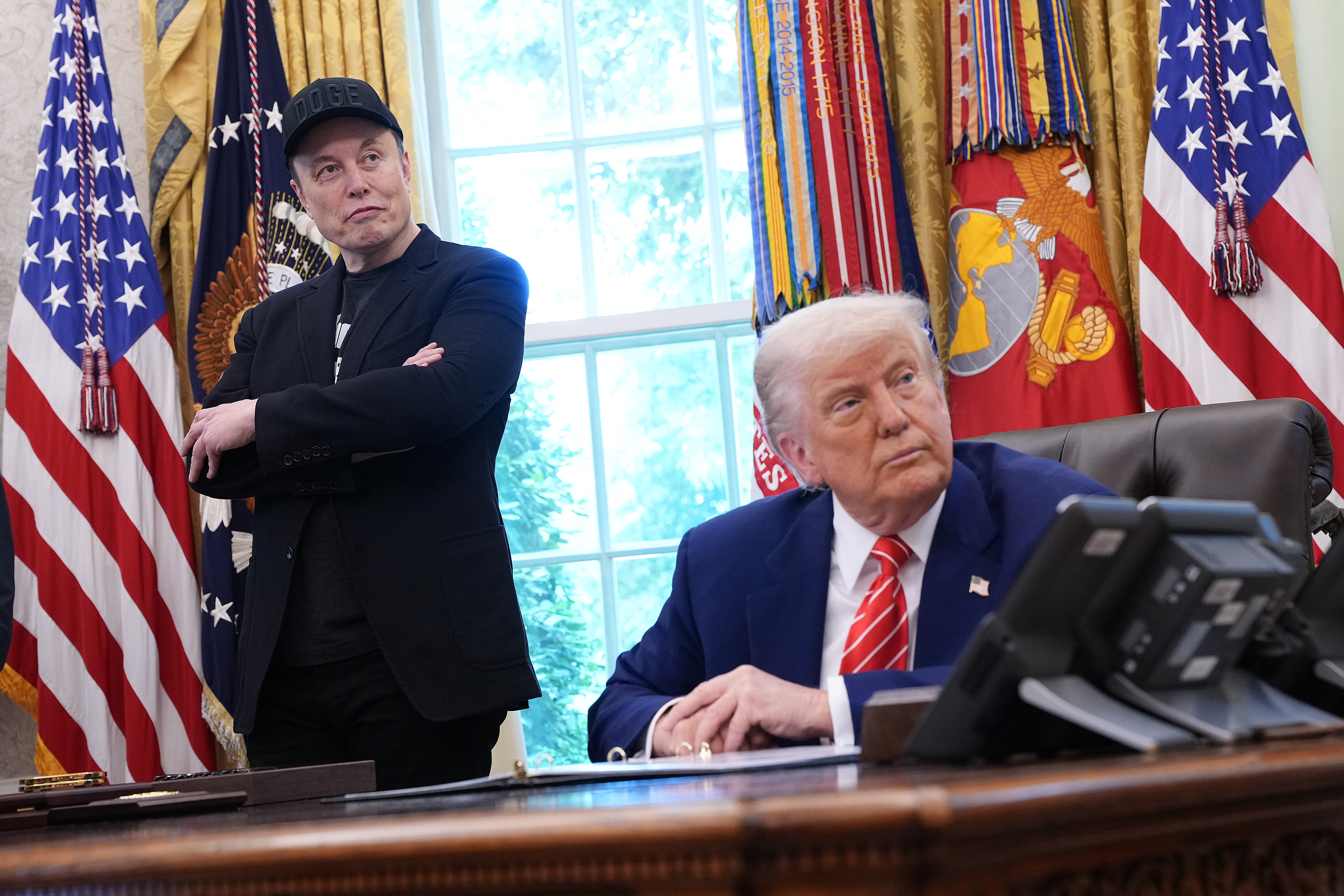 President Trump and his billionaire adviser Elon Musk listen to a question from a reporter in the Oval Office on Friday, as Musk concludes his role leading Trump