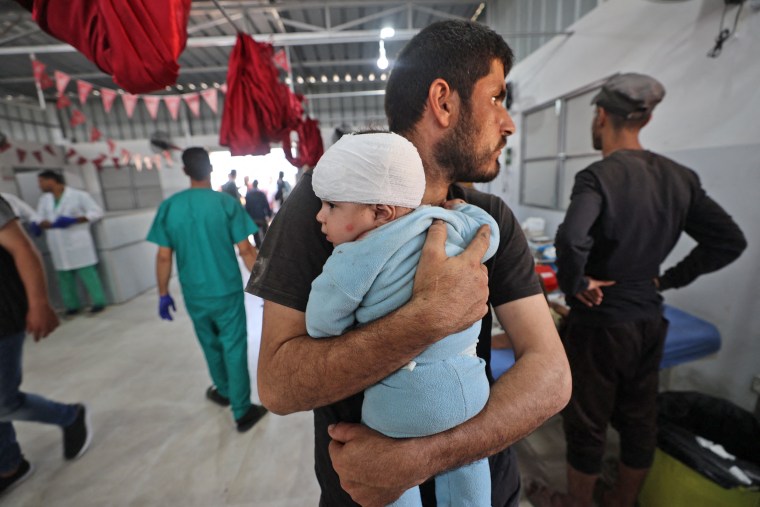A man holds a wounded child after receiving treatment at Al-Awda Hospital in central Gaza.