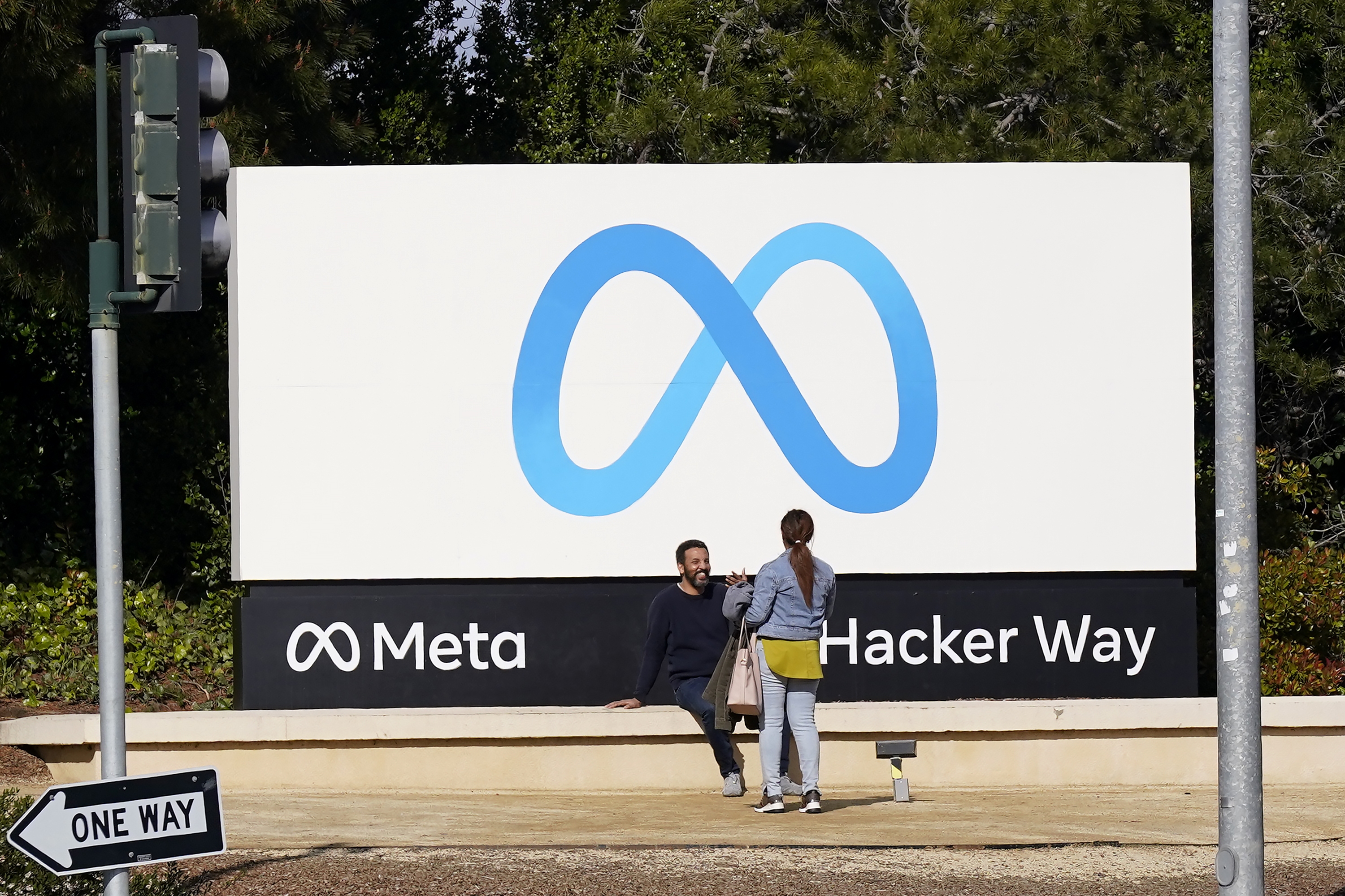People talk near a Meta sign outside of the company