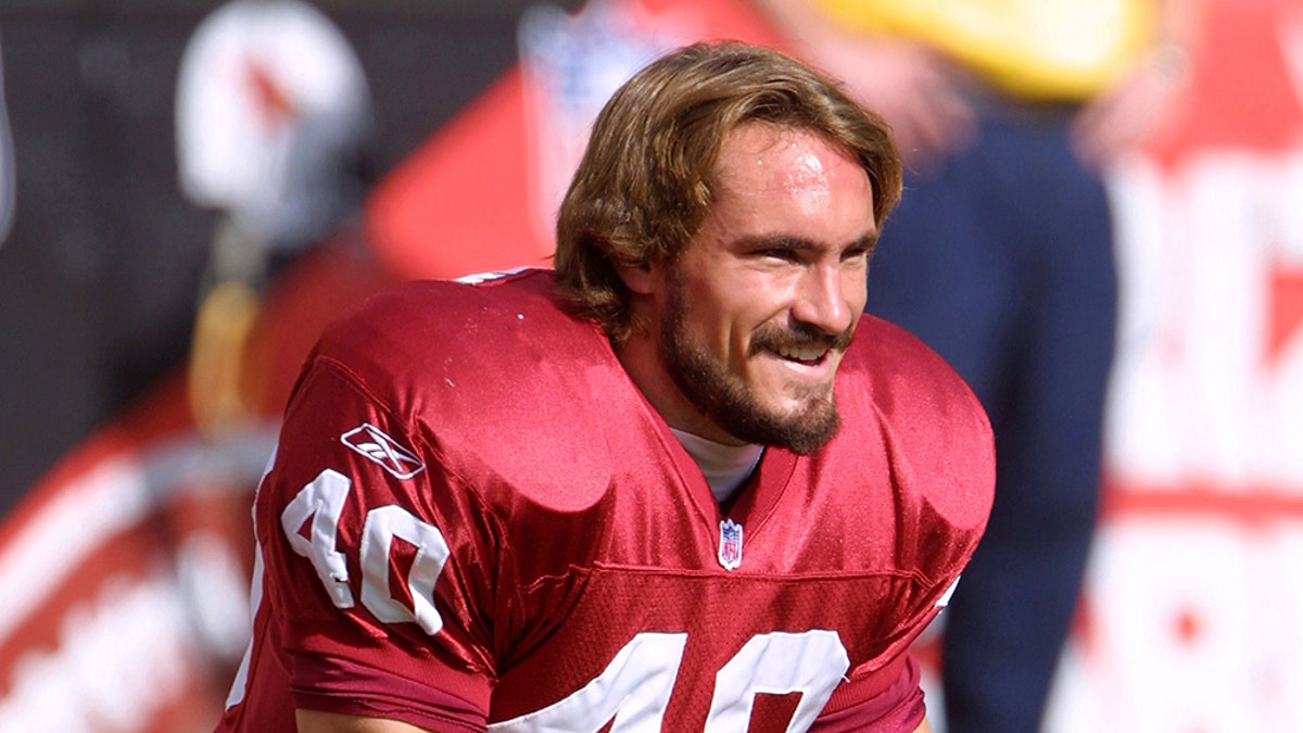 Pat Tillman in NFL gear kneeling on the field.