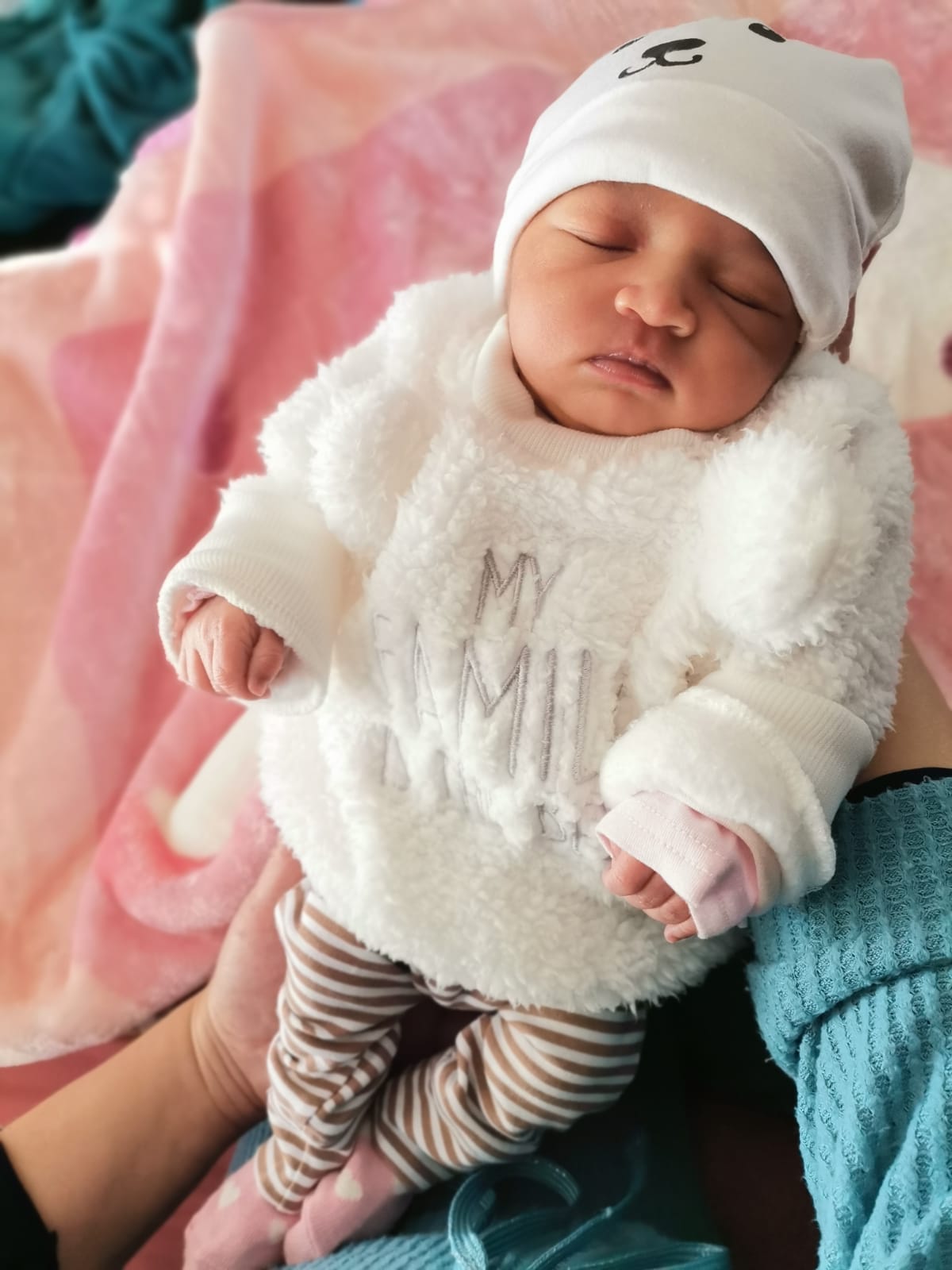 a sleeping infant in a hat and fuzzy sweater
