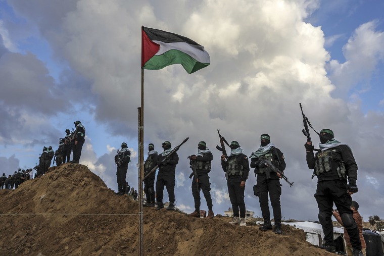 Palestinians stand guard at the site where Hamas handed over the bodies of four Israeli hostages to the Red Cross in Khan Yunis, Gaza, on Feb. 20, 2025.