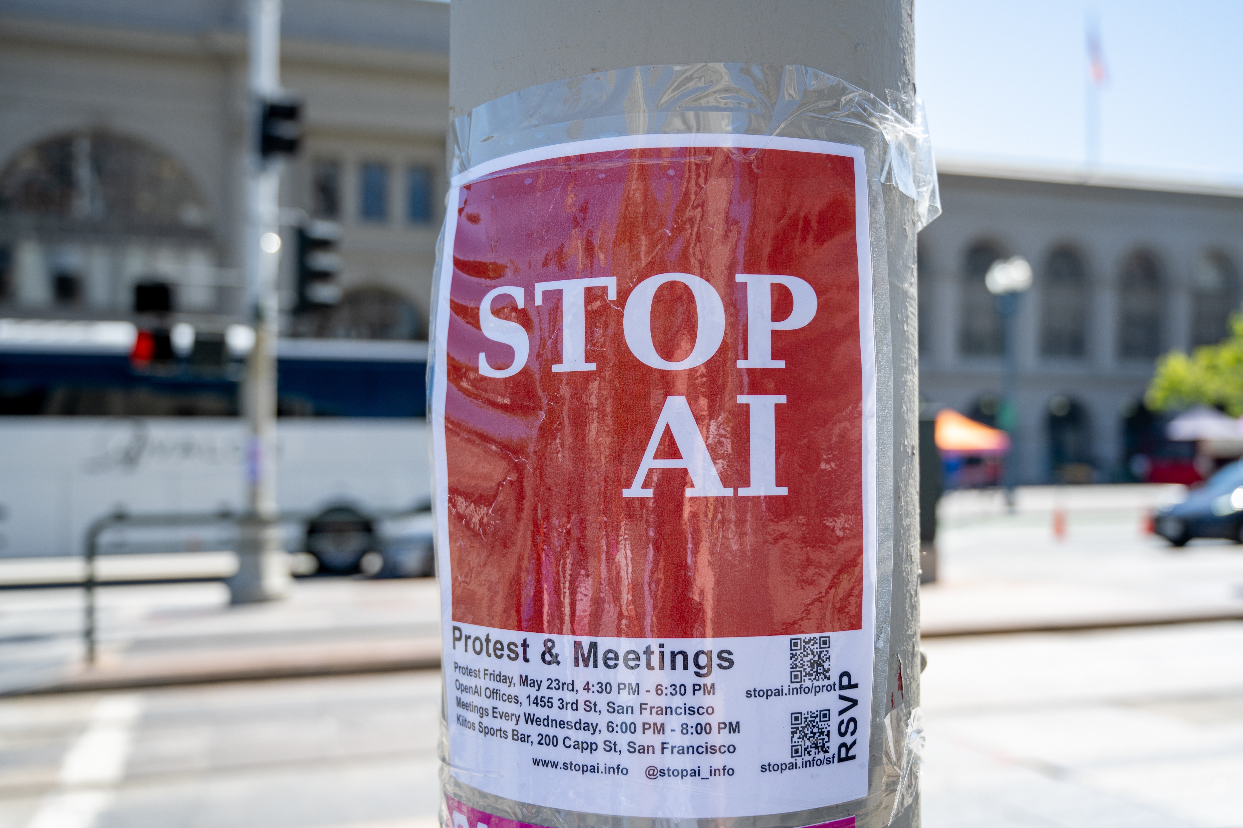 Red STOP AI protest flyer with meeting details taped to a light pole on a city street in San Francisco, California on May 20, 2025.