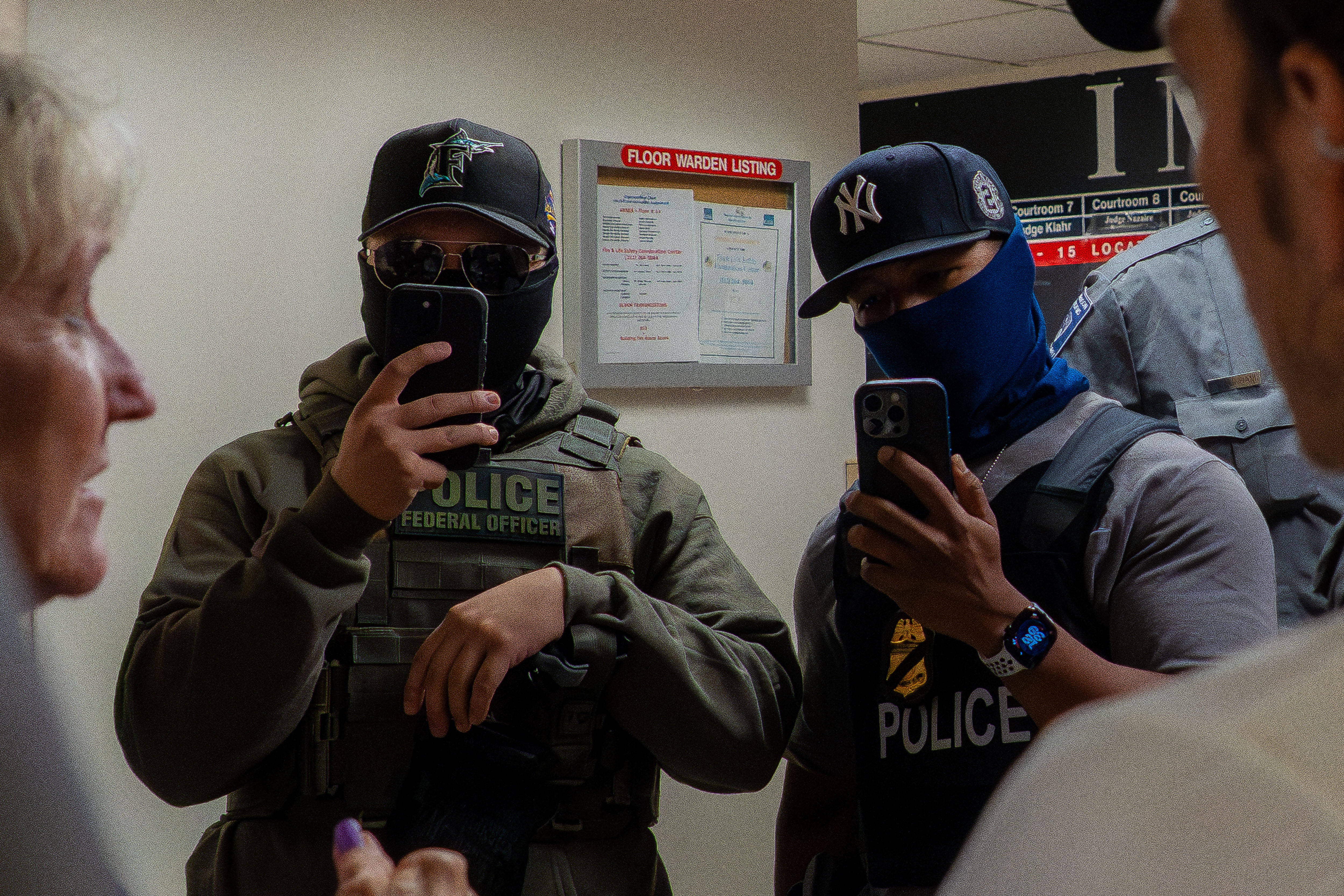 Two ICE agents film the press using smartphones in the hallway outside the immigration court at 26 Federal Plaza in New York USA on July 11 2025. The Department of Homeland Security has been acquiring new tools to identify people and monitor them.