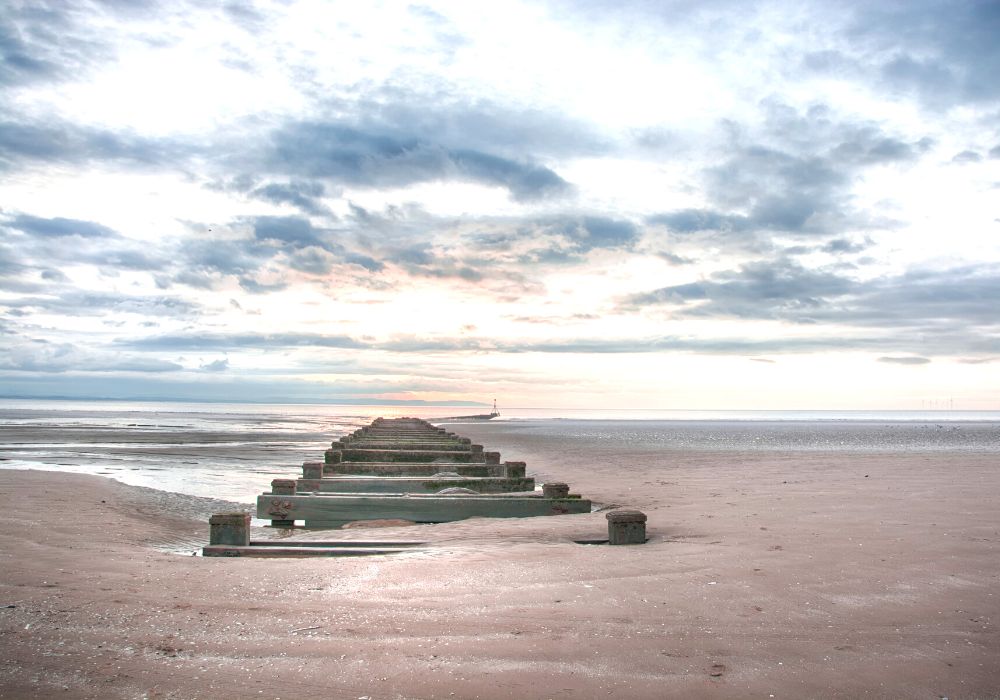 Sunset at Crosby Beach with the pipeline running into the sea at the beach in Liverpool.