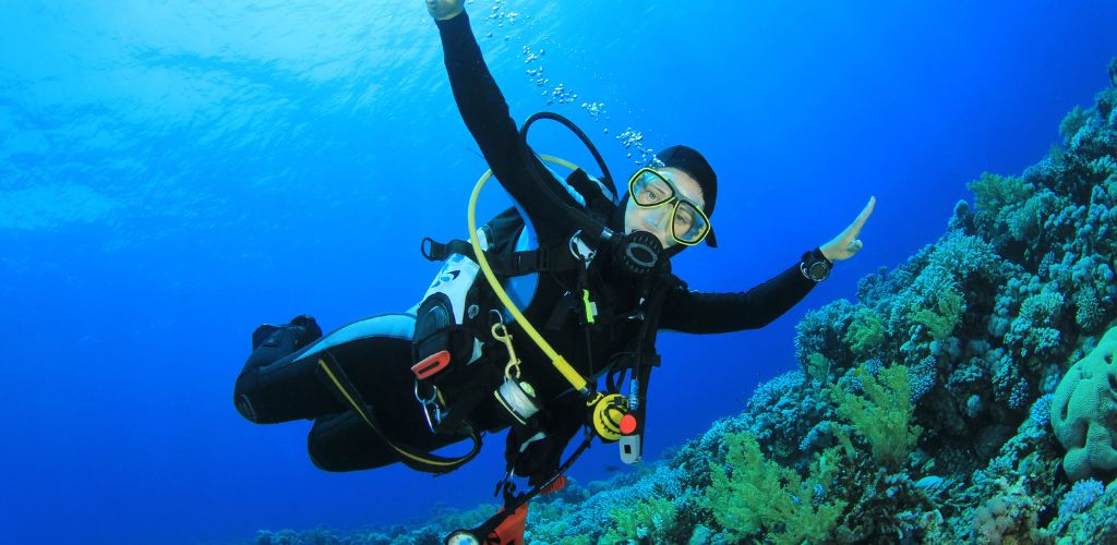 Young woman scuba diver having fun while exploring coral reef.