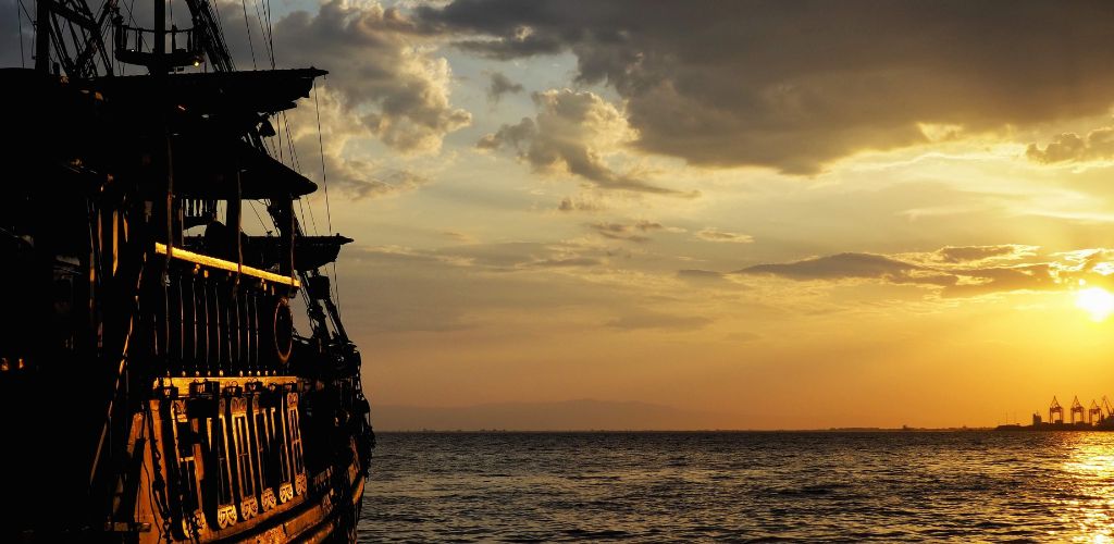 A pirate ship in the water at sunset.