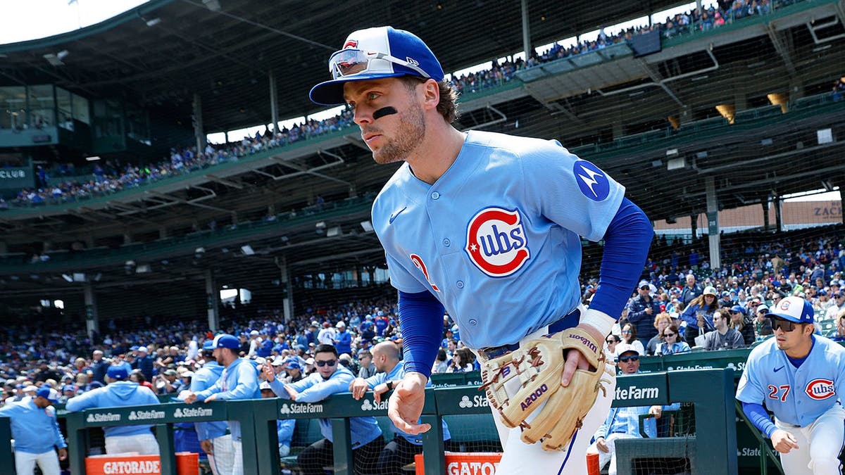 Chicago Cubs second baseman Nico Hoerner running onto the baseball field at Wrigley Field.