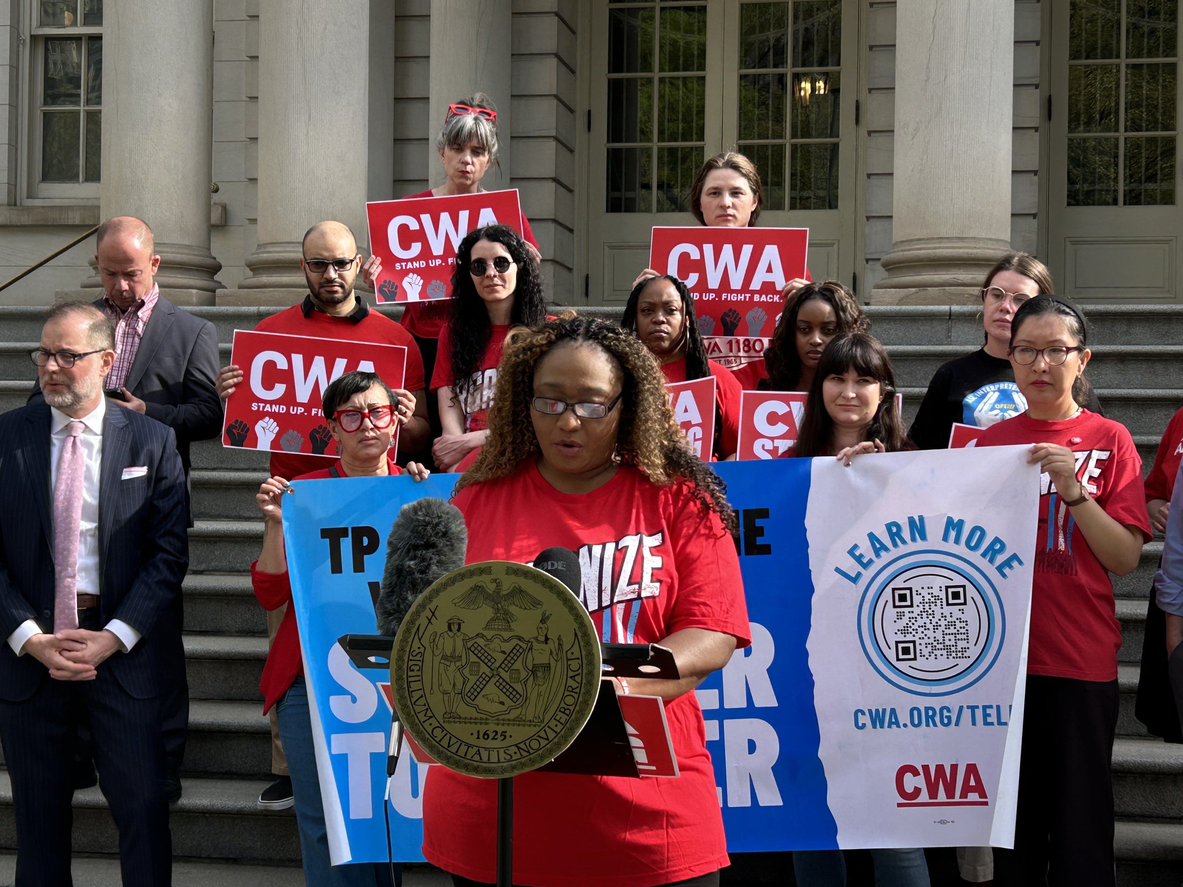 Interpreter Yves Valerus speaks at a LanguageLine press conference in front of New York City Hall in April. LanguageLine interpreters have had their hours drastically cut after the company said it experienced fewer customer demand and started using new scheduling software. Some workers are trying to organize a union.